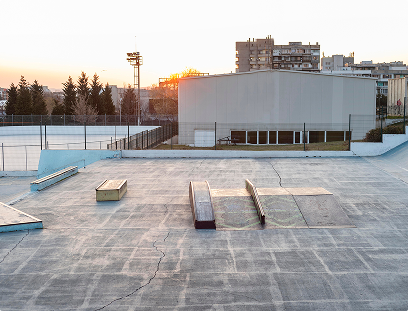 Empty concrete skatepark with ramps and obstacles in urban setting during sunset