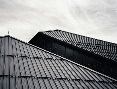 Black metal roof with vertical ridges against an overcast sky